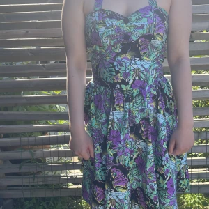 Klänning  - Rockabilly klänning med knytband, kjol  som slutar i knähöjd. Du kommer garanterat vara ensam på festen i den här 