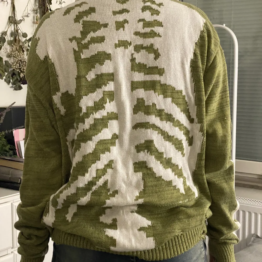 Stickad grön tröja med skelett detaljer på hela ryggen samt armarna! Finns också hål för tummarna:) . Stickat.