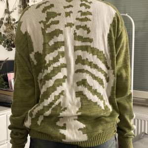 Stickad grön tröja med skelett detaljer på hela ryggen samt armarna! Finns också hål för tummarna:) 
