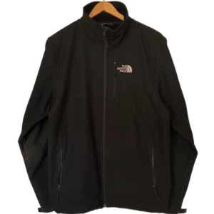 The North Face jacka/windbreaker/fleece/innejacka - En svart tunnare jacka från The North Face. Fleece-material på insidan så bra varm. Storlek M. Spännena på ärmarna är lite trasiga och fläckar som måste tvättas bort. Dm för bilder på det. Annars gott skick. Dm vid intresse och frågor. Läs min bio