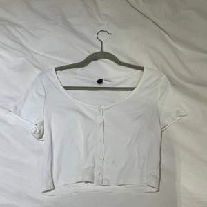 En vit basic t-shirt med knappar framtill. Storlek L men liten i storleken så mer som en M