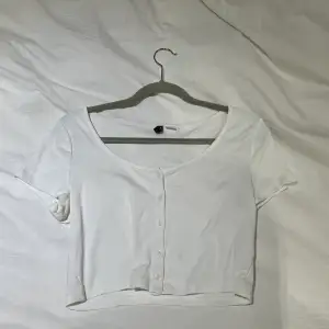 En vit basic t-shirt med knappar framtill. Storlek L men liten i storleken så mer som en M
