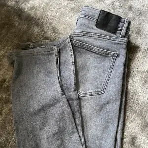 Ett par gråa bootcut jeans med hål och slits i från zara. 