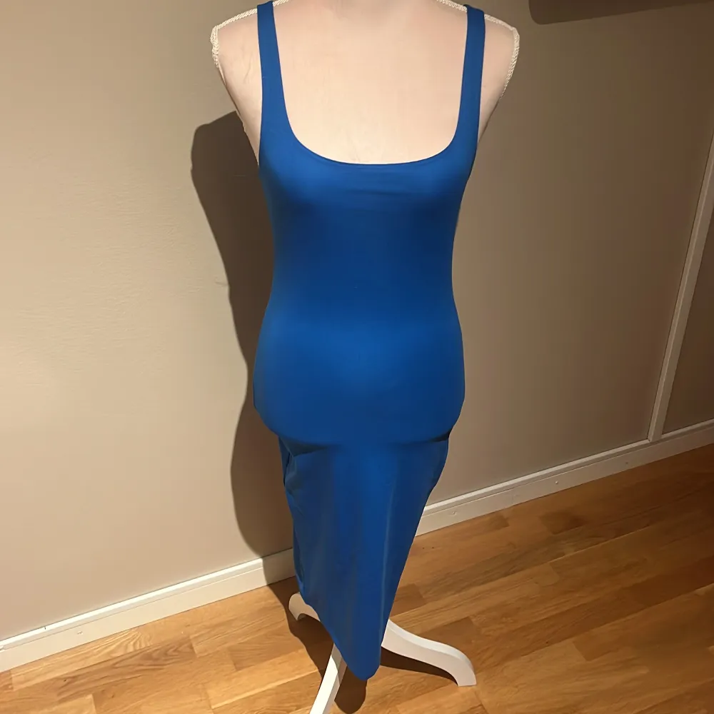 En helt oanvänd blå klänning med prislapp kvar! Har en slits där bak på klänningen! Frakten kostar 65kr!!!. Klänningar.