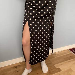 Svartvit prickig H&M kjol, strlk 38 men passar också 36. Om man vill ha den lågmidjad fungerar den också i strlk 34. Kjolen har två slits, ett vid vardera ben.