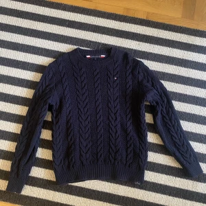 Mönsterstickad Tommy hilfiger tröja - Mörkblå mönsterstickad TH töja i storlek S/xs (164) den är lite stor i storleken så skulle såga 164-170. Helt oanvänd 10/10 skick. Orginalpris 1000 kr