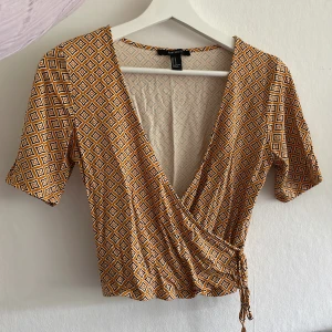 Topp med omlottknyta - Fin, somrig och knappt använd topp med omlottknyte och v-ringning från Forever 21 med ett härligt mönster.