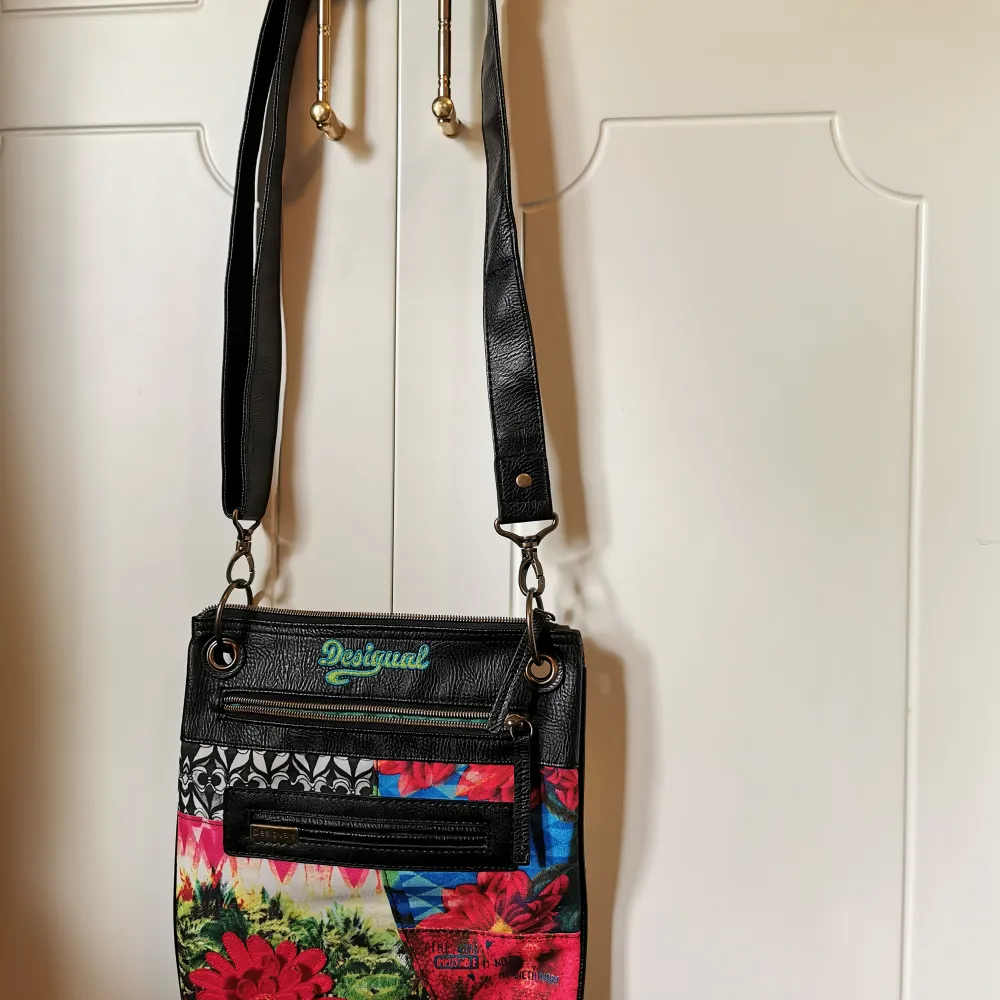Desigual handväska/axelremsväska i måtten 31x25 cm. Två innerfack samt en innerficka med dragkedja. . Accessoarer.