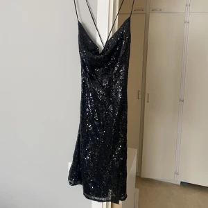 Paljett klänning  - Klänning från Nelly, använd 1 gång, storlek 38, öppen rygg med kors 