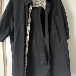 Burberryskjorta - Burberryskjorta, fejk. En lös tråd på en knapp (som man kan fixa själv väldigt lätt), annars i väldigt fint skick. 