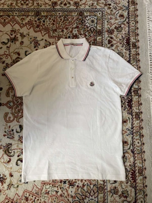 Moncler Polo T-shirt - Vit Moncler Piké i storlek M till salu. NFC skann finns. Den är i nyskick och jättebra kvalite. Skriv gärna om du är intresserad 