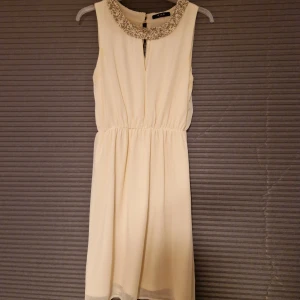 Vit klänning med paljetter - Vit klänning med paljetter i halsen. Från Vila och den är använd sparsamt. Strl M