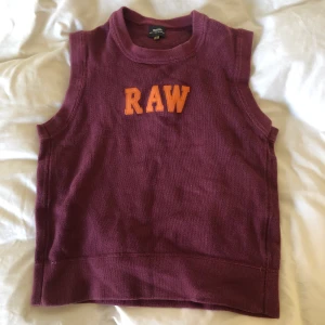 G-star stickad väst strl L - Stickad väst i en varm lila färg med orange text broderad på framsidan. I gott skick, legat orörd i ungefär 20 år. Köparen står för frakt och dm:a gärna vid frågor eller funderingar:)