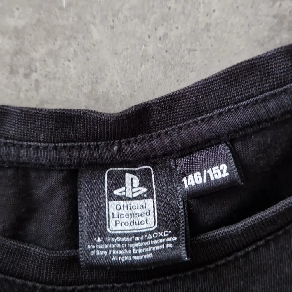 En svart PlayStation tischa, barnstorlek 146-152, 8 av 10.. T-shirts.