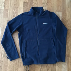 Bergshaus micro fleece - En mörkblå Berghaus microfleece med hel dragkedja fram och dragsko för att justera vidd nertill. Storlek S. Från djur och rökfritt hem
