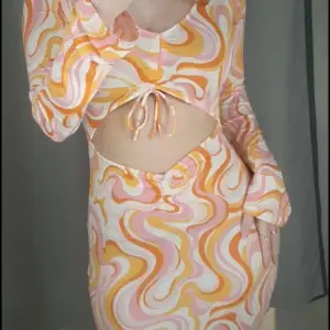 Kort klänning med rosa/orange mönster. Aldrig använd.