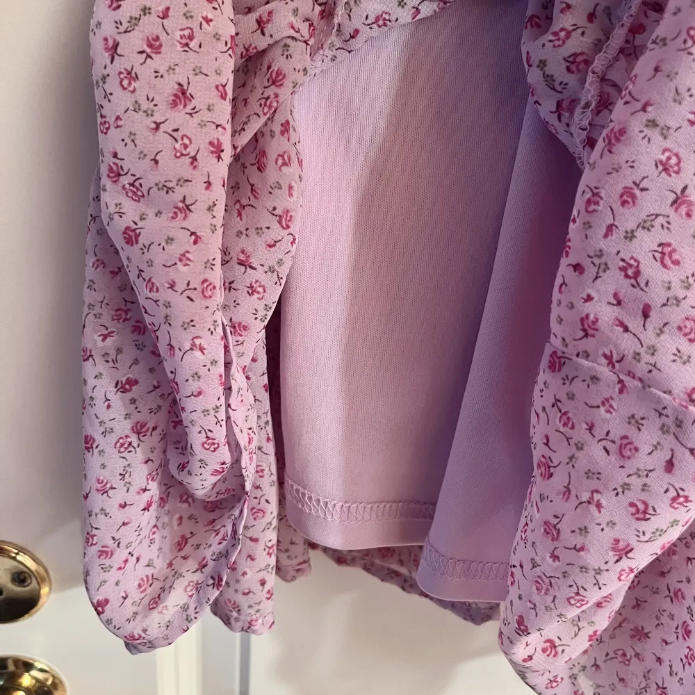 Gullig lila volangklänning med rosa blommor. Klänningen har knytbara band och stretch i ryggen, passar xs/s. Endast använd vid 3 tillfällen. Klänningar.