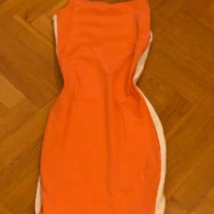Orange klänning med vita streck på längs sidorna. I mycket bra skick och knappt använd 🤍