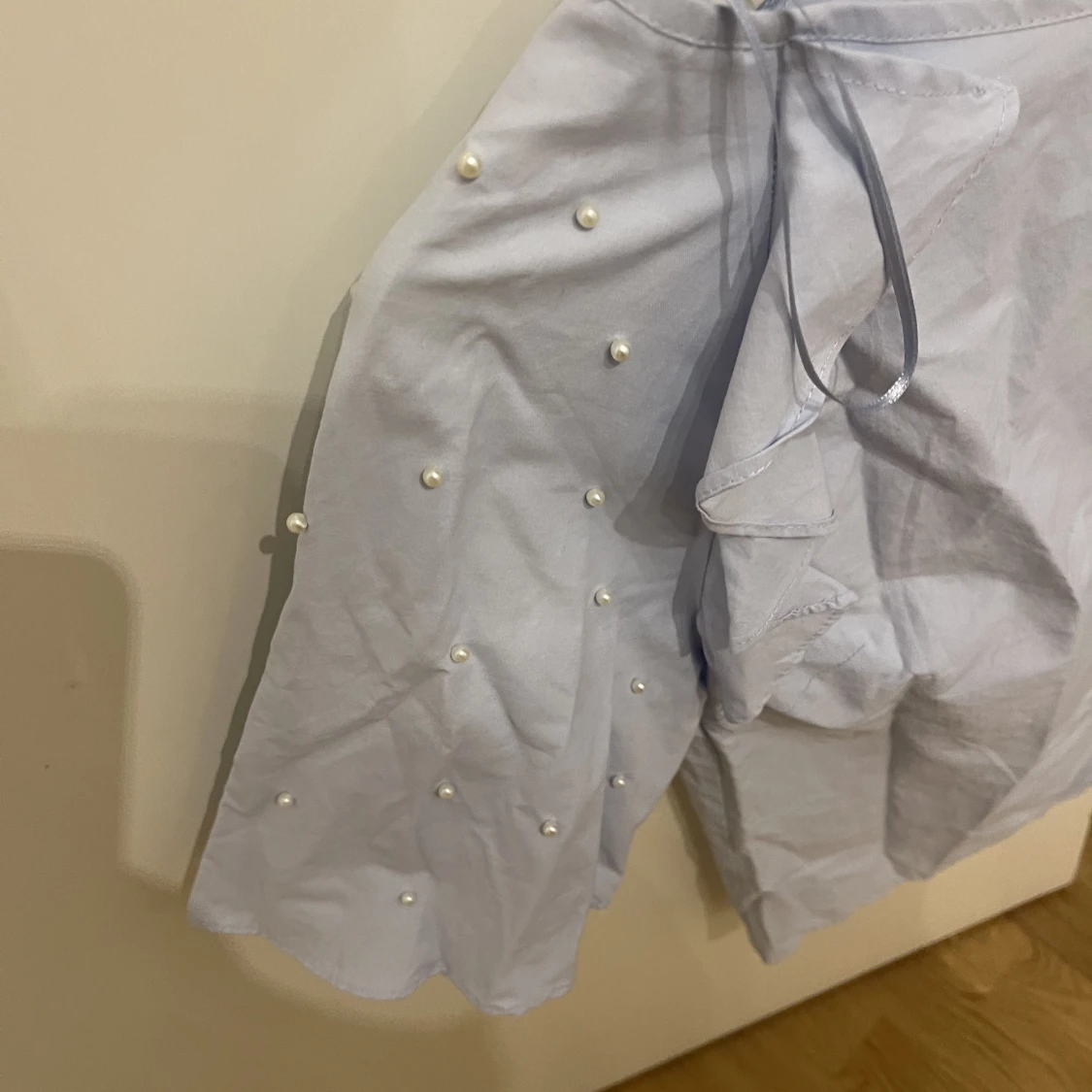 Ljusblå topp med vita pärlor på ärmen  - 90