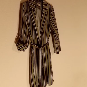 Tunn kappa - Tunn kappa med fina detaljer; slits i sidor, skärp, ärmarna kan användas på olika sätt. fint skick