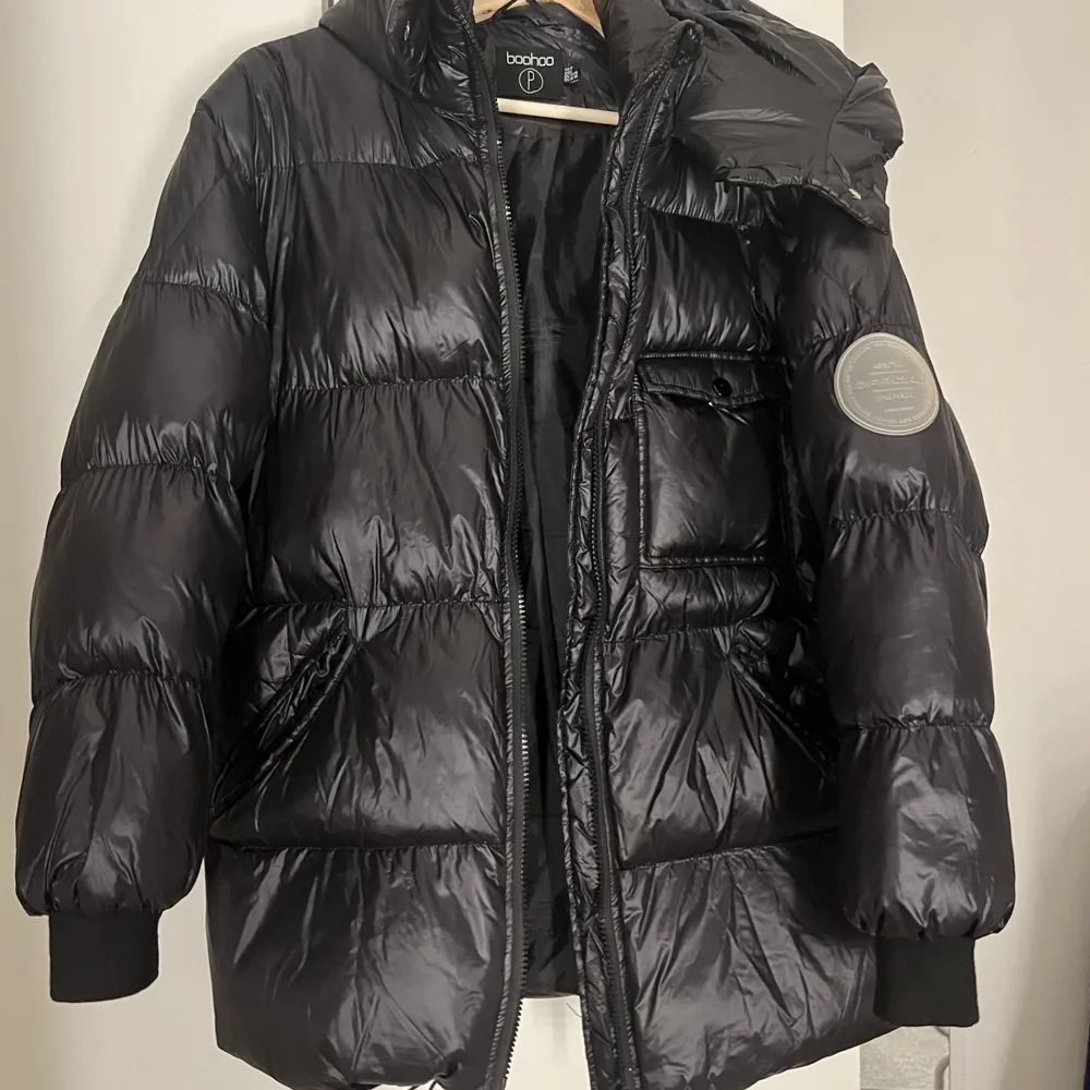 En svart, glansig lite längre puffer jacket från Boohoo, är i väl skick och väldigt varm, perfekt vinterjacka!!. Jackor.