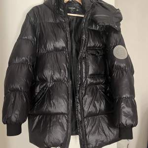 En svart, glansig lite längre puffer jacket från Boohoo, är i väl skick och väldigt varm, perfekt vinterjacka!!
