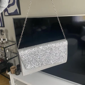 Väska  - En kuvert väska med ett långt axelband man kan justera, använd 1 gång 