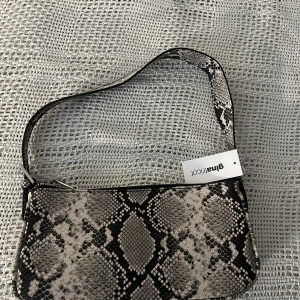 Handväska  - Helt ny väska. Snakefärgad. Lappen finns kvar. Originalpris 299 kr. Säljer för 89 kr exklusive frakt. 