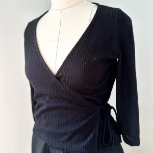 Svart topp i omlott - Svart topp från Mango.  Aldrig använd med etikett kvar i plagget.  Storlek: M  Dockan på bilden: Storlek S