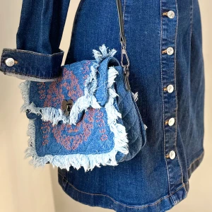 Crossbody från Desigual - Supersnygg väska från Desigual 💙Låses med hjärtat i mitten och har tre inre fack + ett fack med blixtlås.  Jeansklänningen på bilden finns att köpa.  Storlek: Ca 26 x 18  