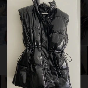 Svart glansig väst från HM - I princip oanvänd väst från HM. Strl S. Kan justeras i midjan, bra figur!