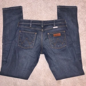 Low Waist Wrangler Jeans - Säljer ett par superfina jeans från Wrangler i bra skick! Jeansen är straigh leg. På lappen är storleken 26 men jag skulle säga att de passar 24/25. Midjemått tvärsöver= 37 cm  Innerbenslängd= 77 Köparen står för frakt, hör av er vid frågor!