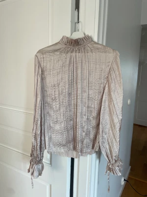Fest blus - Champagne färgad fest blus från h&m! Lappen kvar, endast testad! Volang i ärmarna med knyte.🩵