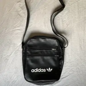 Aspraktisk svart axelväska från Adidas! Remmen går att reglera efter behov och själva väskan är rymlig med fack. Skriv för mer info!💋