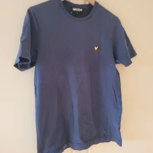 Lyle&Scott tshirt blå stlM - T-shirt Lyle&Scott marinblå i bra skick. Litet hål i tyg vid söm/bak vid lappen i nacken. Fraktkostnad tillkommer.
