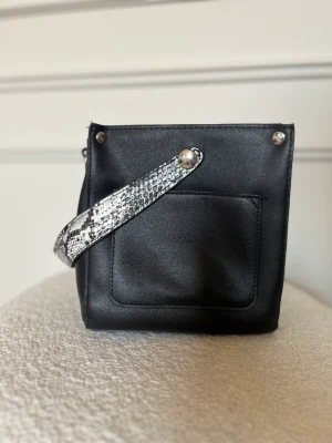 Svart väska  - Svart liten handväska men rymlig. Finns även med axelrem. 