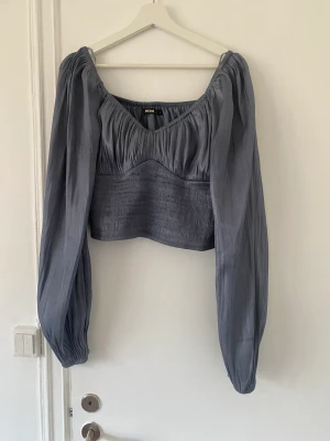 Topp med puffärmar - Blå/silvrig topp med puffiga ärmar.  Använd endast en gång. 