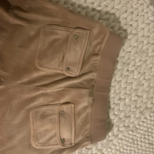 Juicy byxor beige - Jag fick dem i julas som julklapp, nytt skick men knapparna på smörerna har gått av, de går att limma tillbaka. Jag säljer för att de inte längre kommer till användning och är för långa på mig. Nytt pris är 1100.
