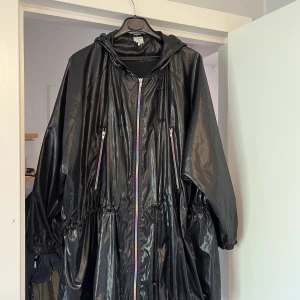 Tunn vind/regn jacka från monki - Snygg oversize jacka i glansigt tyg med flerfärgad dragkedja. Går att dra åt i midjan och nertill.