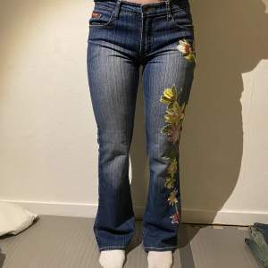 Extremt fina vintage jeans från ”XFN jeans”. Broderade blommor. Mått: midja 38cm. Grenmått: 21cm. Lår: 25cm. Innerbenslängd: 77cm. Benöppning: 23cm. 