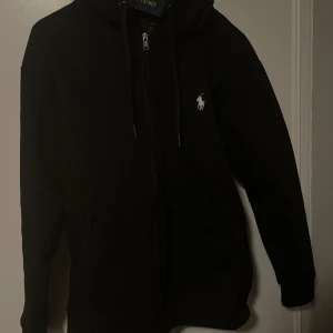 Ralph Lauren kofta - Hej!  Säljer en helt ny ralp lauren zip hoddie. Storlek S men kan kanske passa M. Helt ny aldrig använd prislapp kvar!  Ny pris 2000kr. Mitt pris är 795kr. Vid frågor och funderingar är de bara höra av er. 