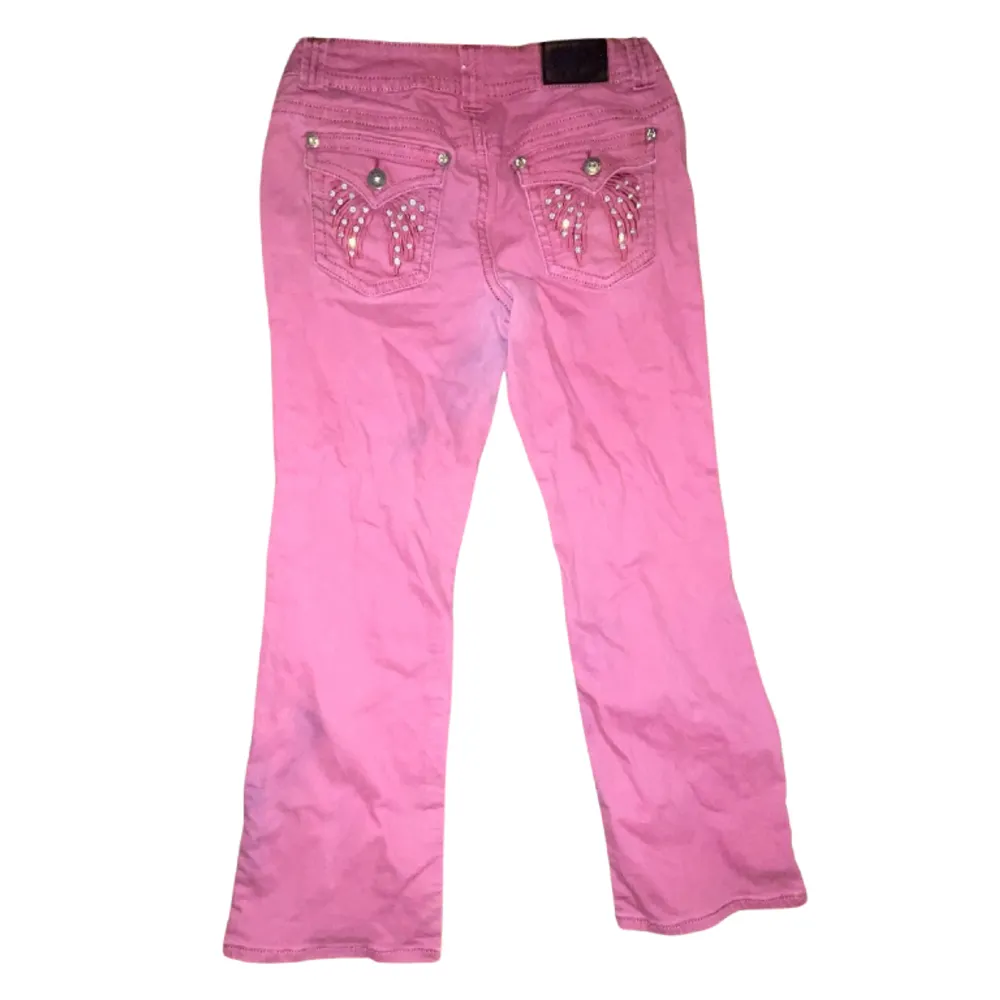 Your pink Arizona boot-cut jeans rock a cold sign on the back pocket with prime stone wing details, low waist, and a touch of bling. Plus, a subtle stain adds a hint of lived-in character. Farkut & Housut.