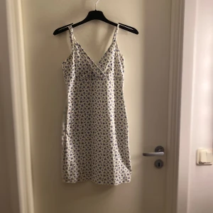 Klänning - Blommig kort klänning, lite genomskinlig, går att justera axelbanden. Bra skick.