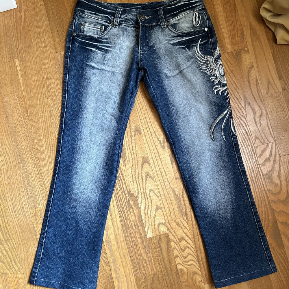 Lågmidjade Bootcut Jeans som liknar crazy age med en cool drake på benet💙  Innerbenslängden: 67cm Midjemåttet tvärsöver: 40cm❣️. Jeans & Byxor.