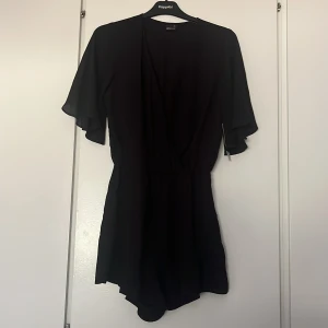 Svart byxdress - En svart byxdress från ginatricot med prislappen kvar på, luftigt och skönt tyg med fina detaljer 