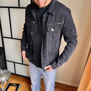 Nudie Jeans co jacka  - Svart jeansjacka från Nudie Jeans säljes.  Storlek L men skulle säga att den är ganska liten i storleken så funkar även för en M (och även för en S om man vill ha oversized).