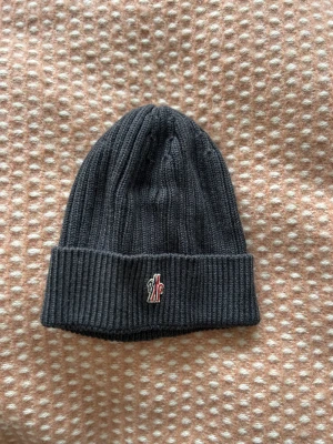 Moncler Gui  - 🤝🏻, Moncler mössa som jag ej använder längre.  (Osäker ifall jag ska sälja den) men vill se vad ni kan ge för den;)   Köptes från deras egna hemsida för 2 år sedan för 1800kr.   Kan säkert hitta tagsen till den, har allt i en låda någonstans 🤌🏻