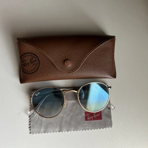Ray-bans blåa - Ray-ban model ”round metal” med blått glas och guldig frame. Knappt använda och är i nyskick! Superfina men märker att dom inte används längre så därav säljer jag! Nypris 1900:-. Vill man ha bild på hur dom ser ut på så skriv till mig så fixar jag!