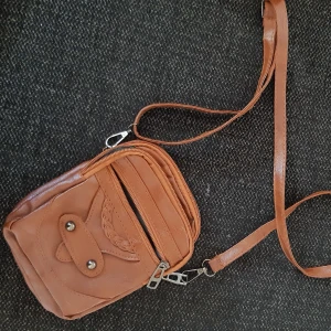 Liten brun handväska väska  - Liten söt väska  helt ny ,läder liknande matrial med axelrem ,köpt för 349 kr ,stod äkta läder men tvivlar på att det är det. Finns 3 fack ..se bild 