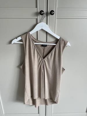 Linne  - Linne i beige färg med flätad detalj fram från Vila: strl M